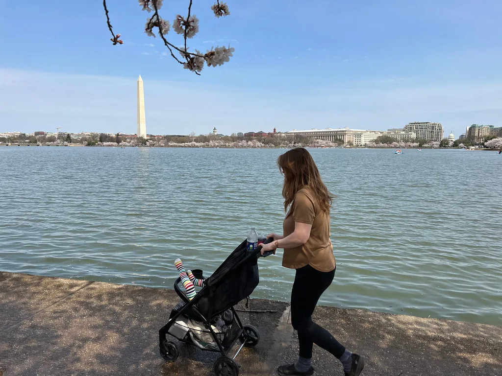 Parent marchant à côté de son enfant qui fait ses premiers pas en extérieur