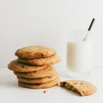 Pile de cookies moelleux au chocolat posés à côté d un verre de lait sur un fond blanc