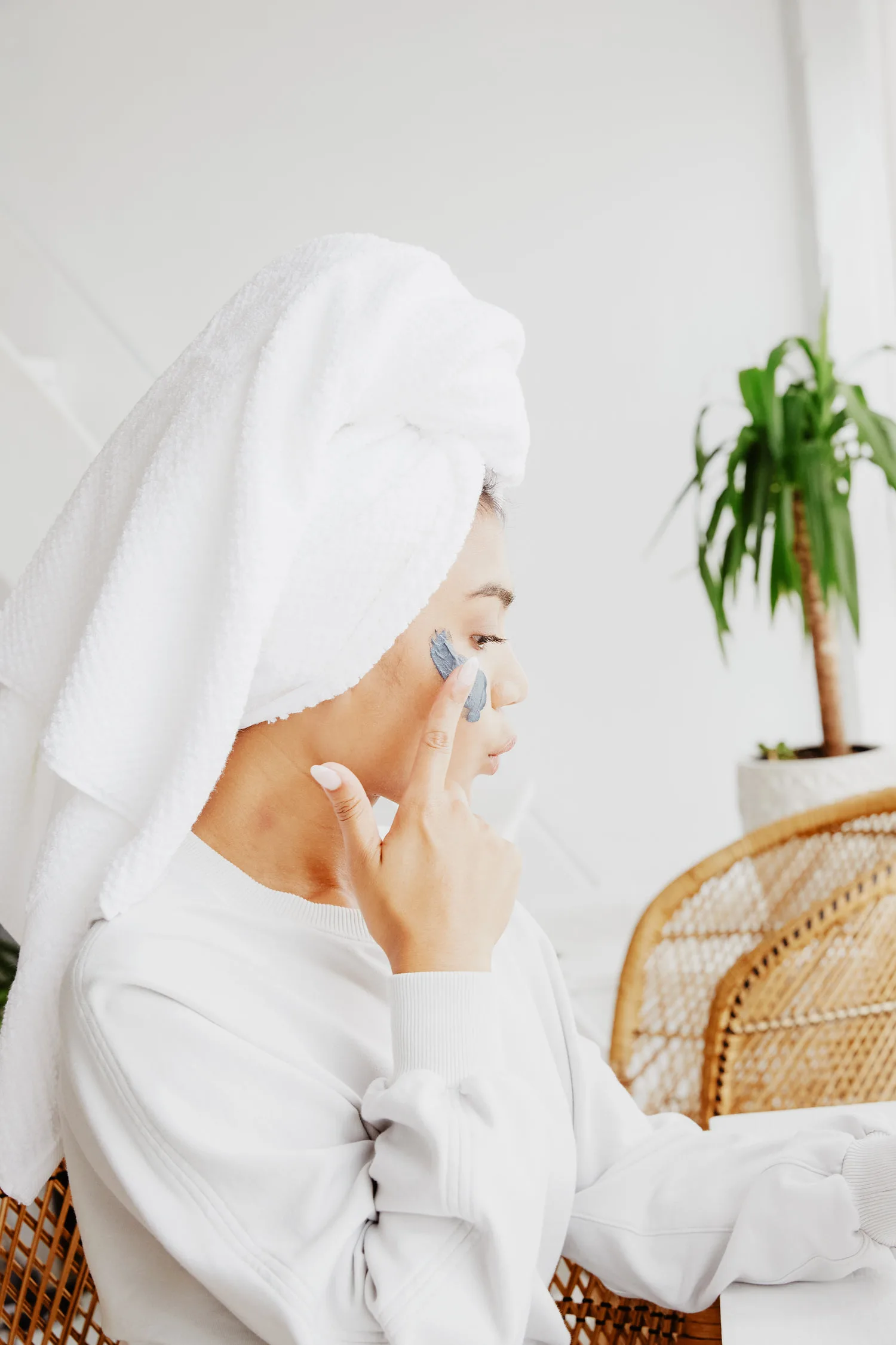 Femme appliquant un masque visage hydratant du bout des doigts sur ses joues