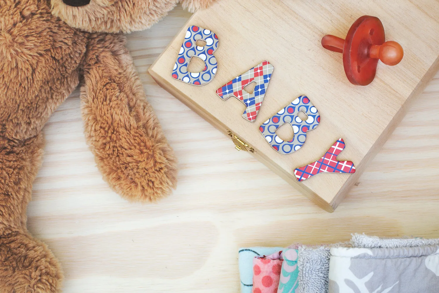 Flatlay chambre de bébé avec un ours en peluche, une tétine vintage et des langes colorés