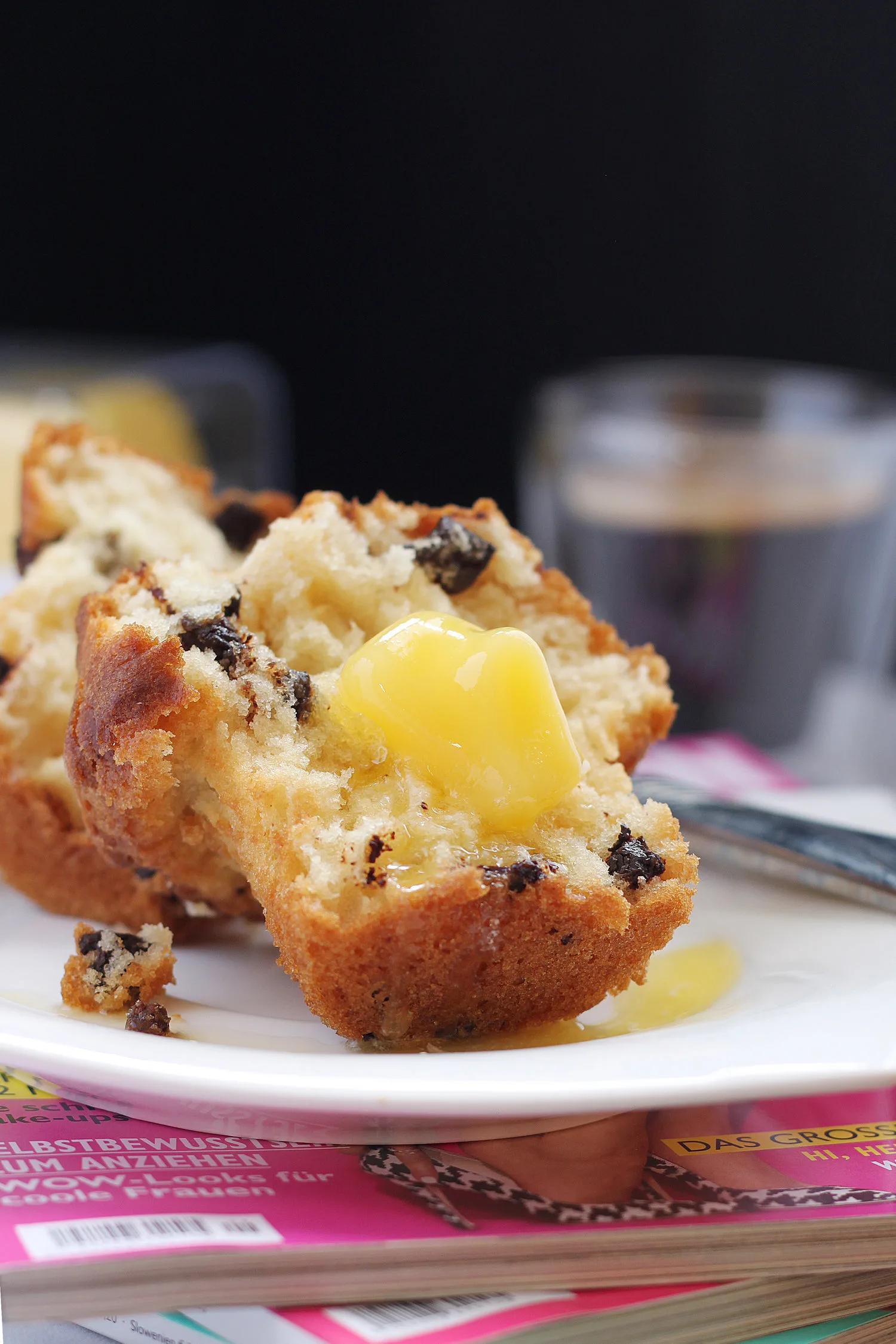 Muffin aux pépites de chocolat ouvert avec un carré de beurre fondant et un café noir