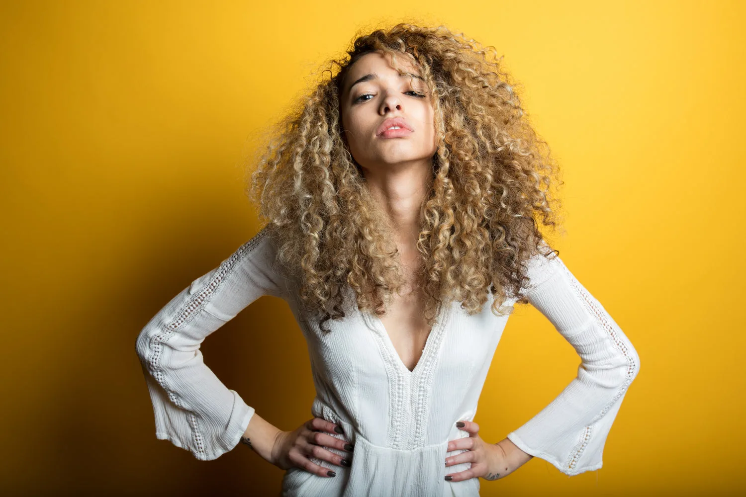 Portrait éditorial d une jeune femme confiante aux cheveux bouclés sur fond jaune