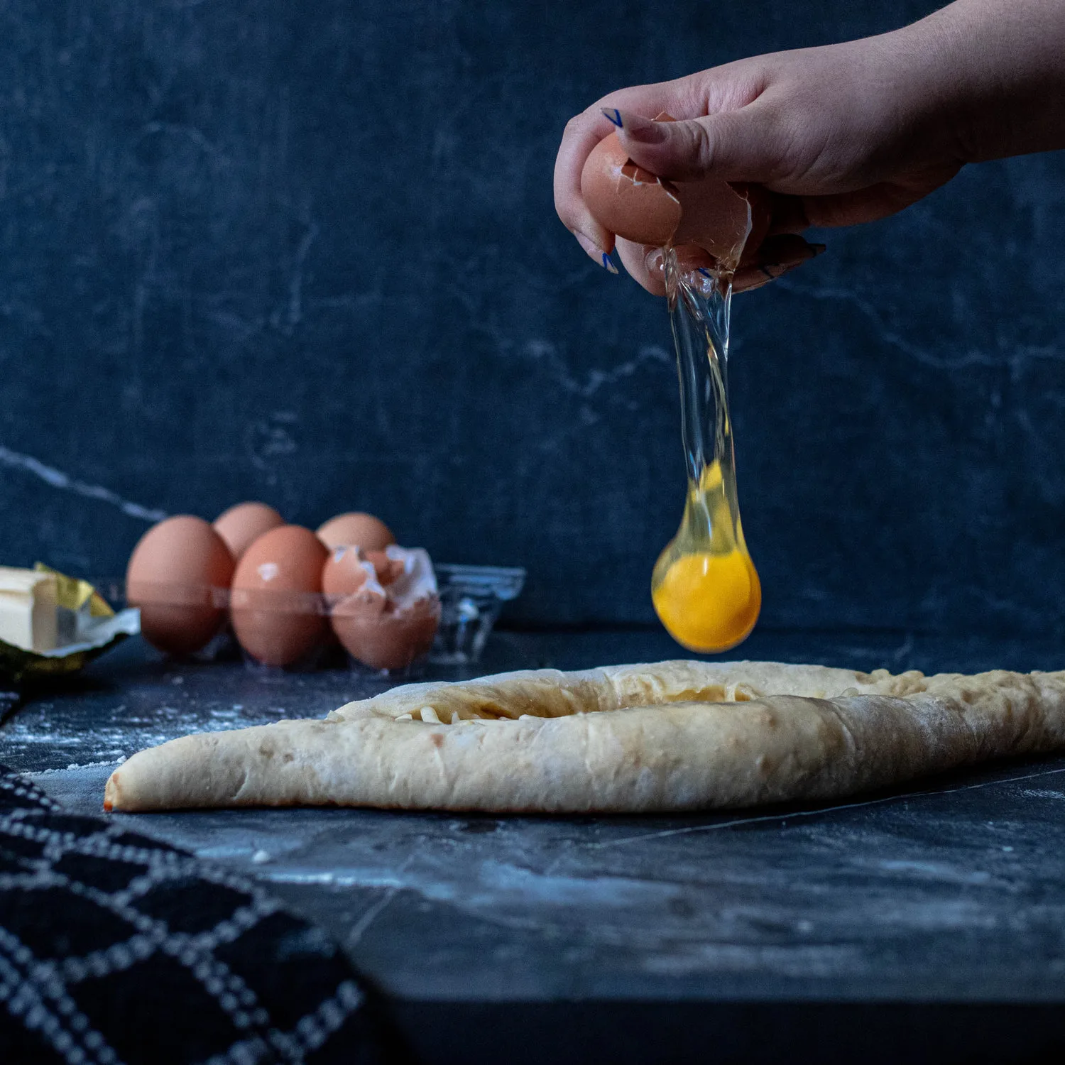 Main cassant un œuf frais au-dessus d une préparation de gâteau sur un plan de travail en marbre