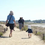 Famille marchant ensemble sur une plage de sable fin au coucher du soleil