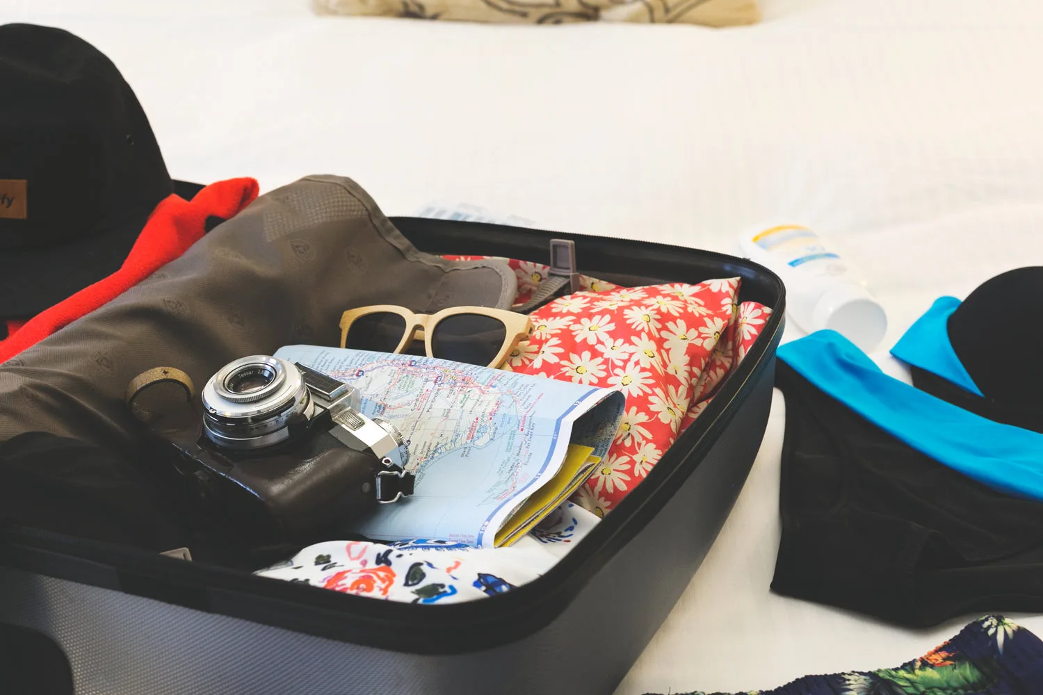 Valise ouverte remplie d accessoires de voyage, appareil photo, lunettes et vêtements