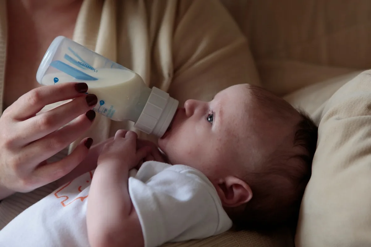 Mère donnant le biberon de lait infantile à son bébé dans un cadre chaleureux