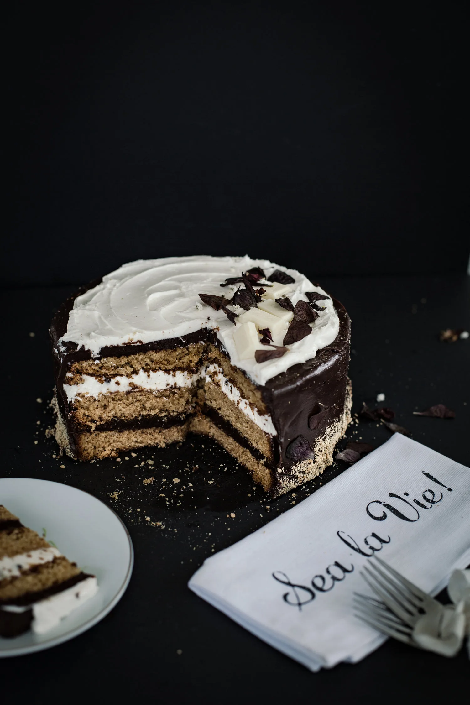 Layer cake à la génoise fourré de chantilly et ganache chocolat coupé sur fond sombre