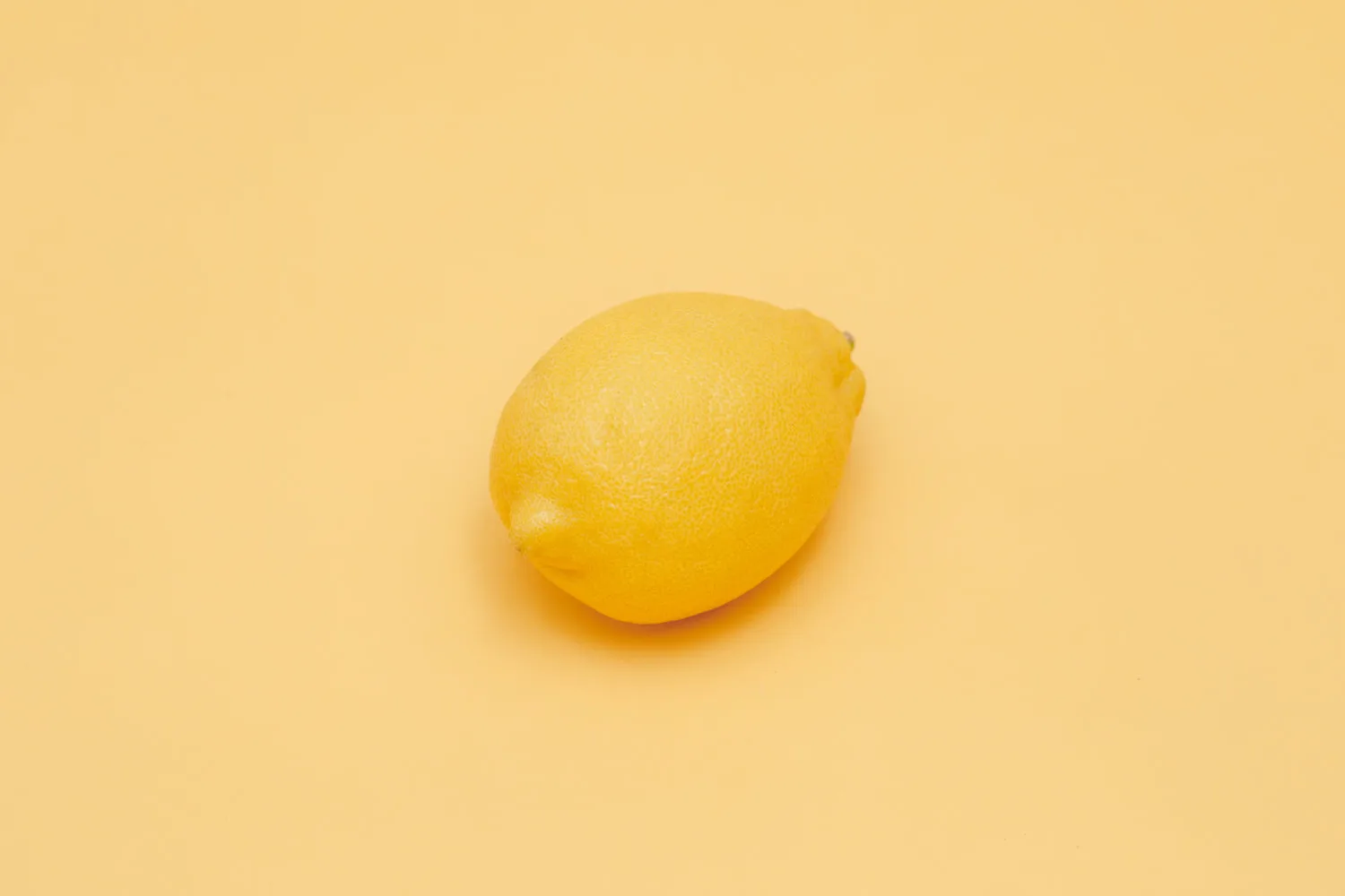 Citron jaune entier parfaitement mûr posé sur fond jaune uni en studio