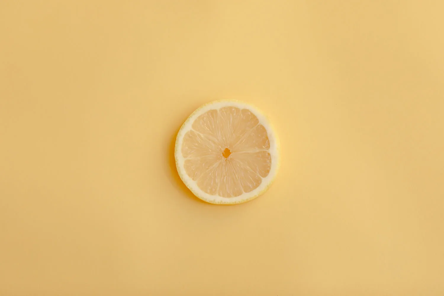 Tranche de citron jaune fraîche et juteuse posée sur fond jaune vif