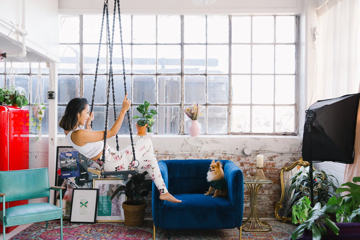 Loft chic avec tapis persan coloré, canapé bleu nuit et grandes fenêtres industrielles