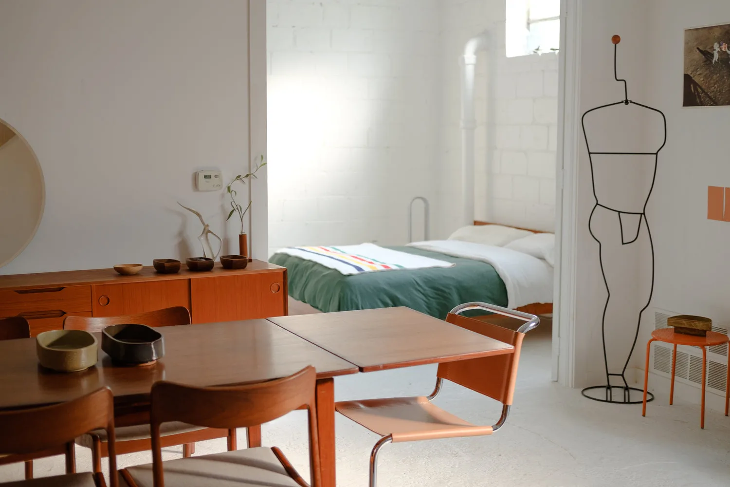 Appartement open-space mid-century moderne avec table en bois, chaises design et vue sur chambre