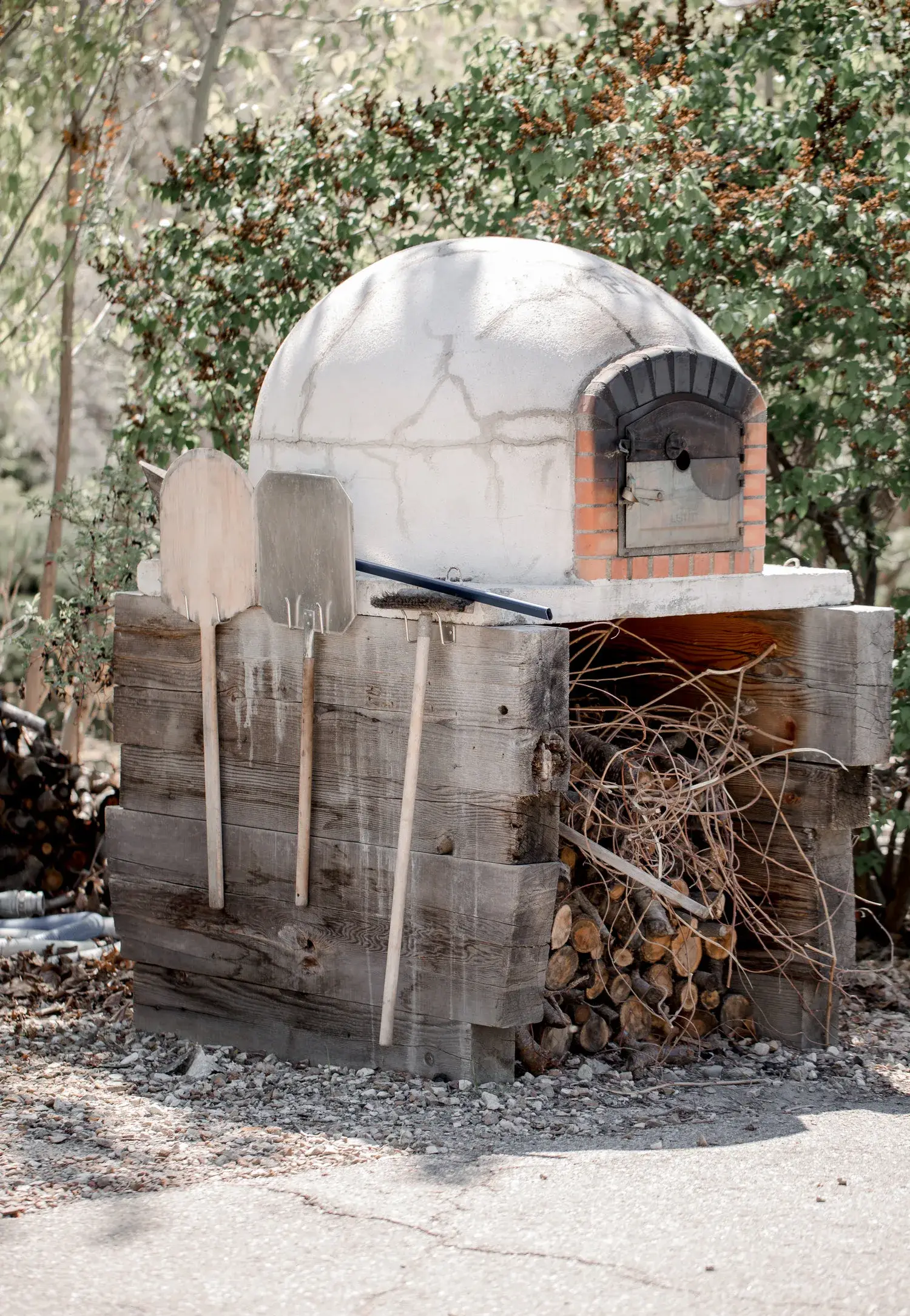 Four à pizza en pierre en extérieur avec pelle en bois et bûches empilées