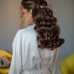 Femme de dos aux longs cheveux bruns bouclés brillants en peignoir de soie blanc