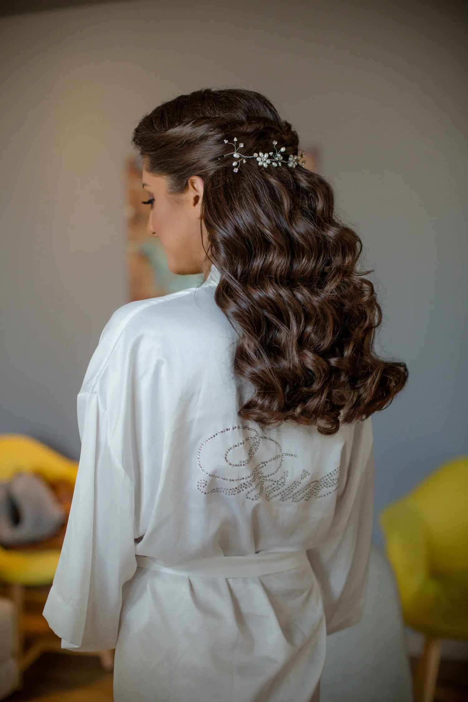 Femme de dos aux longs cheveux bruns bouclés brillants en peignoir de soie blanc