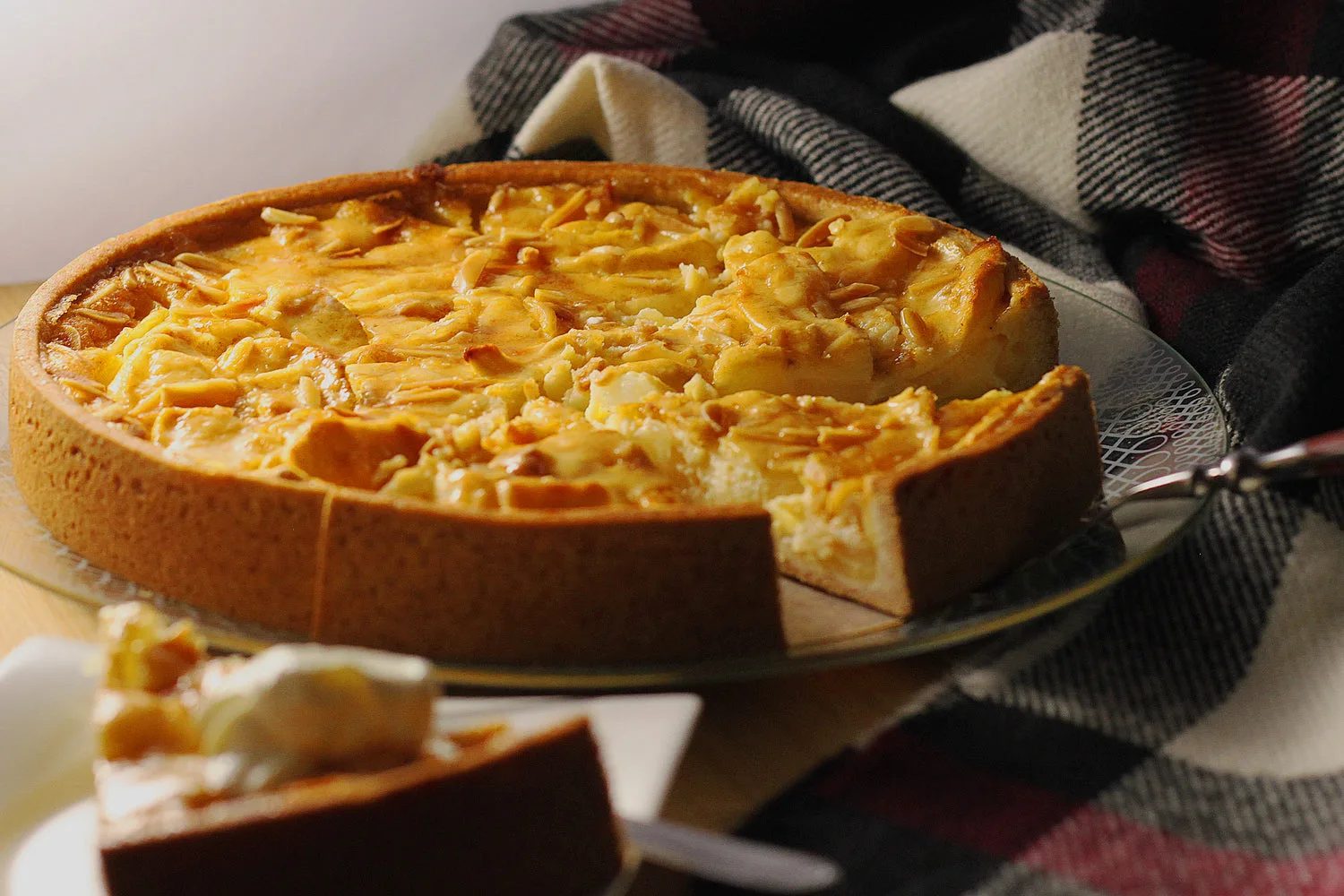 Tarte aux pommes épaisse coupée avec une part et une quenelle de crème fraîche