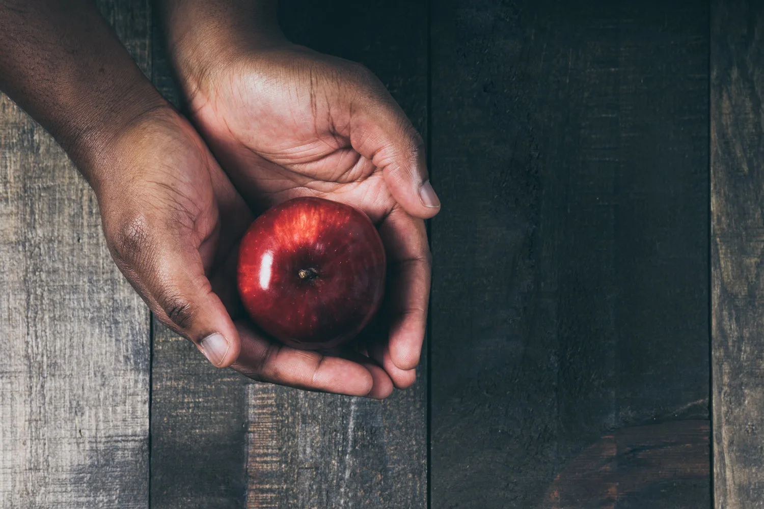 Belle pomme rouge tenue dans deux mains au-dessus d une table en bois rustique