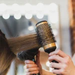 Femme se faisant brosser et sécher les cheveux avec une brosse ronde en salon