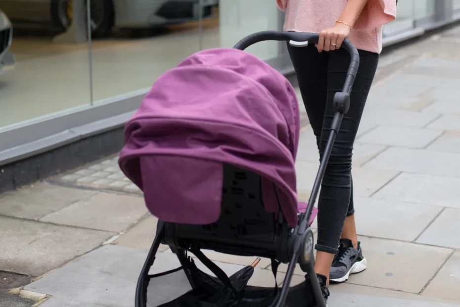 Jeune maman poussant une poussette violette dans une rue commerçante urbaine